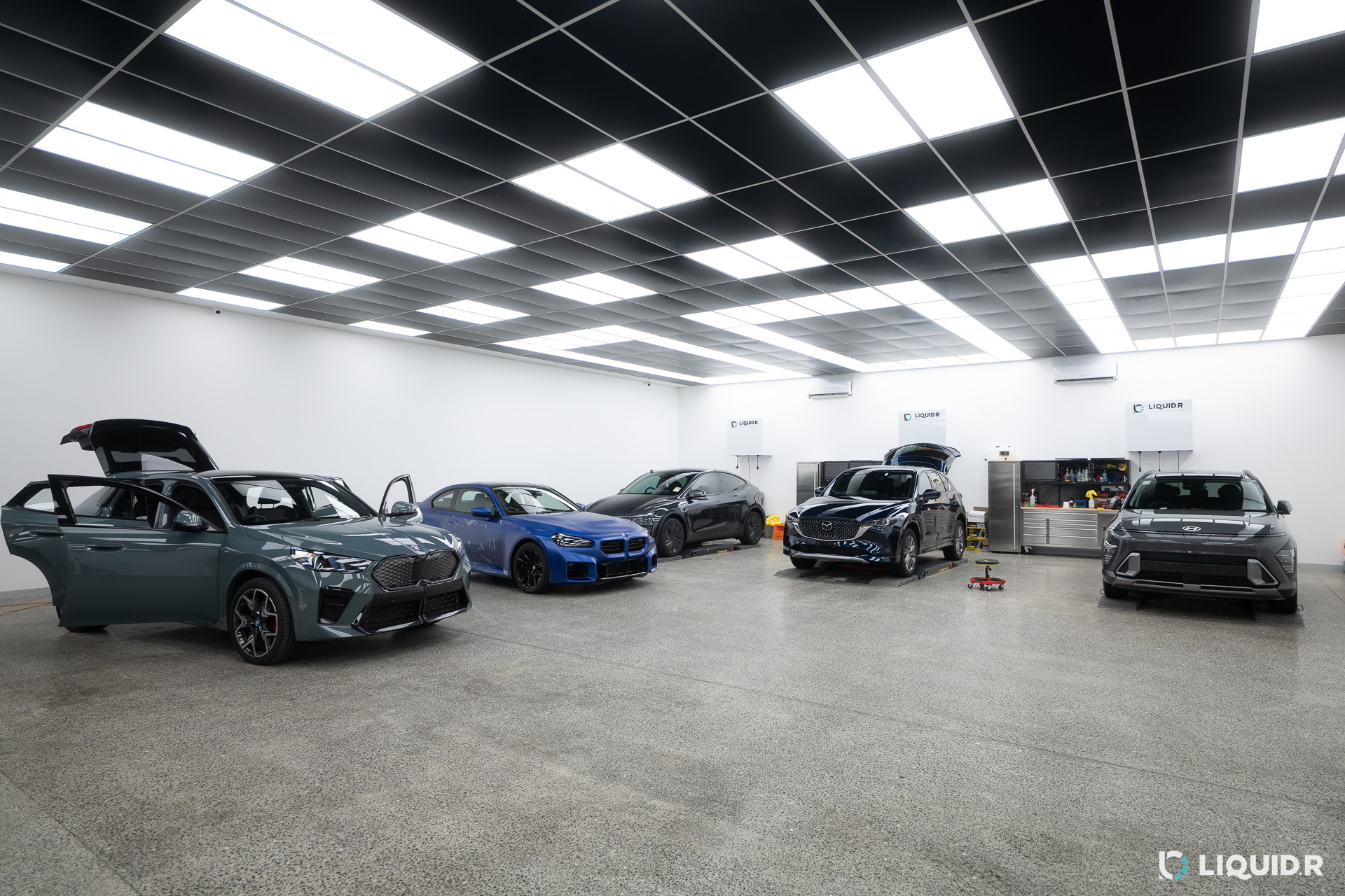 Liquid R Mitcham workshop floor with customer cars lined up under the lights
