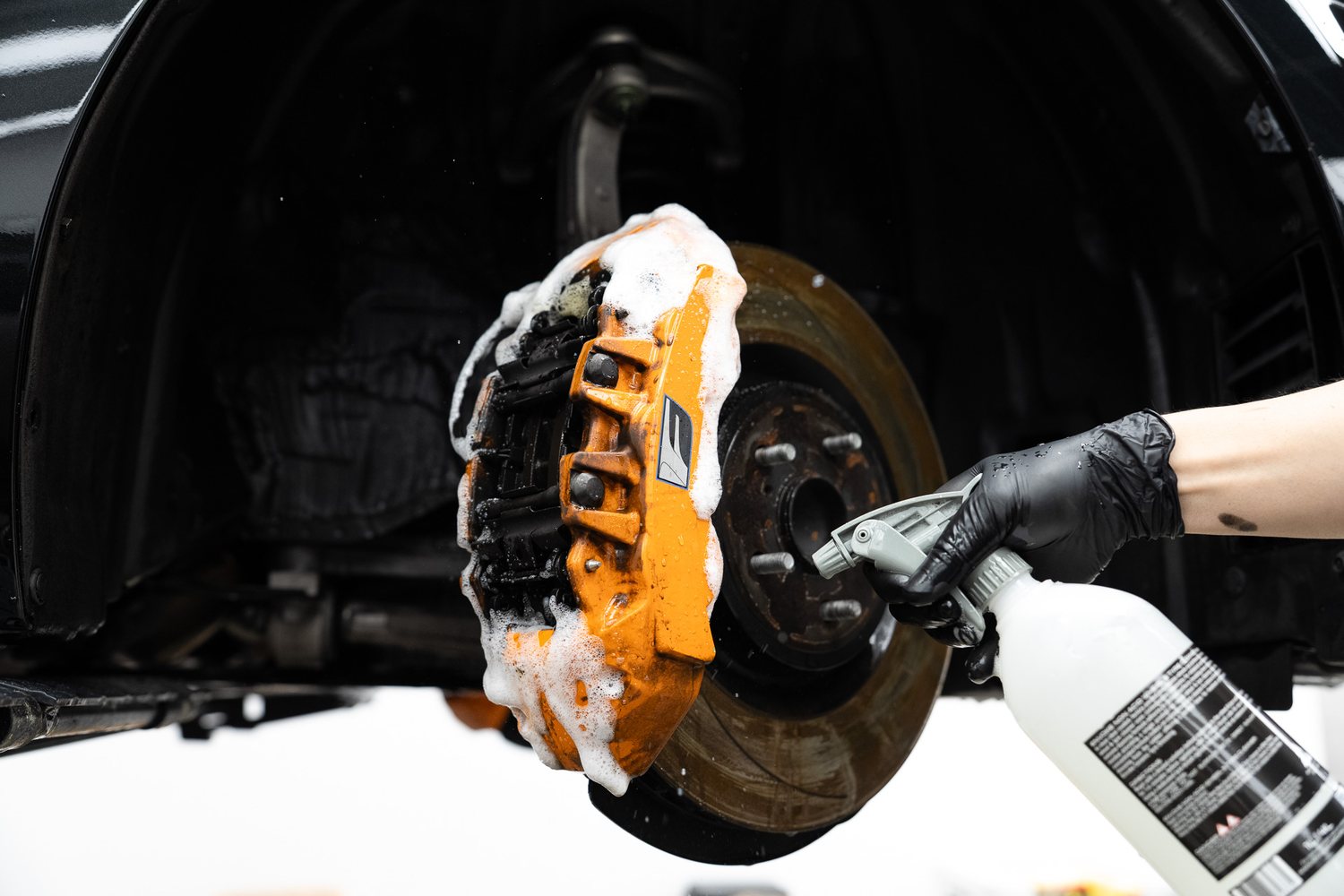Brake caliper being cleaned with foam and a brush