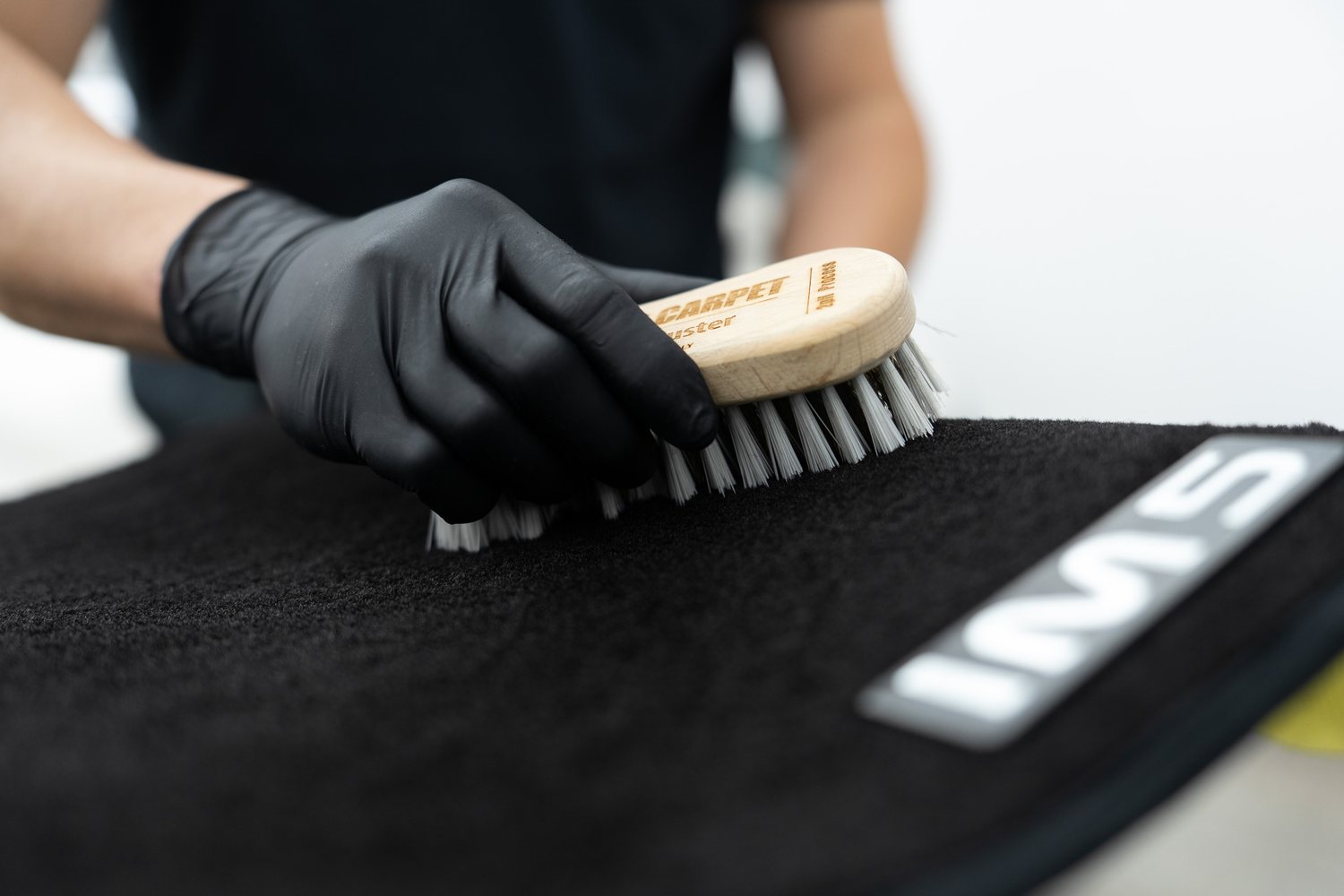 Brush lifting dirt from a carpet mat