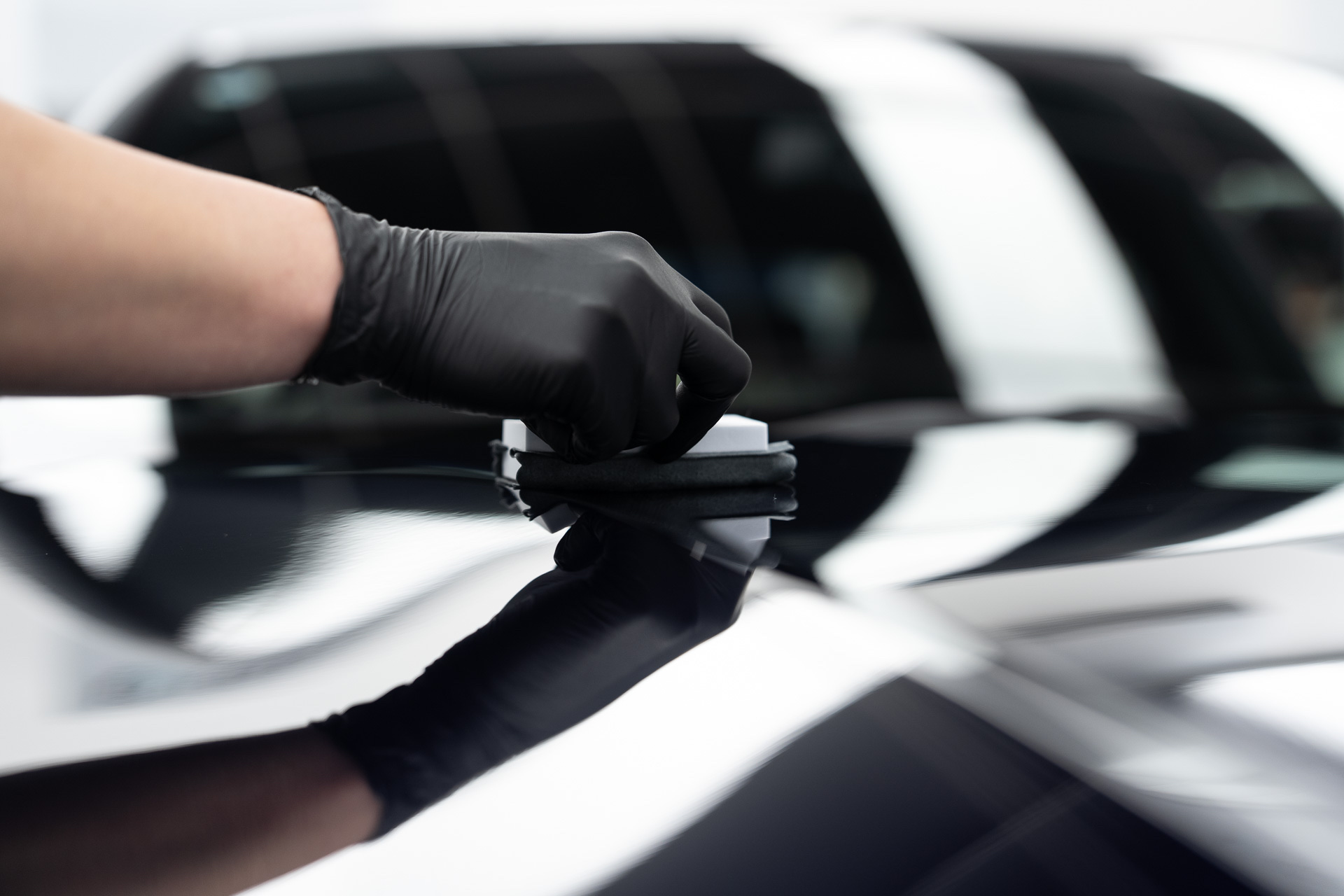 Technician levelling a ceramic coating on a black panel
