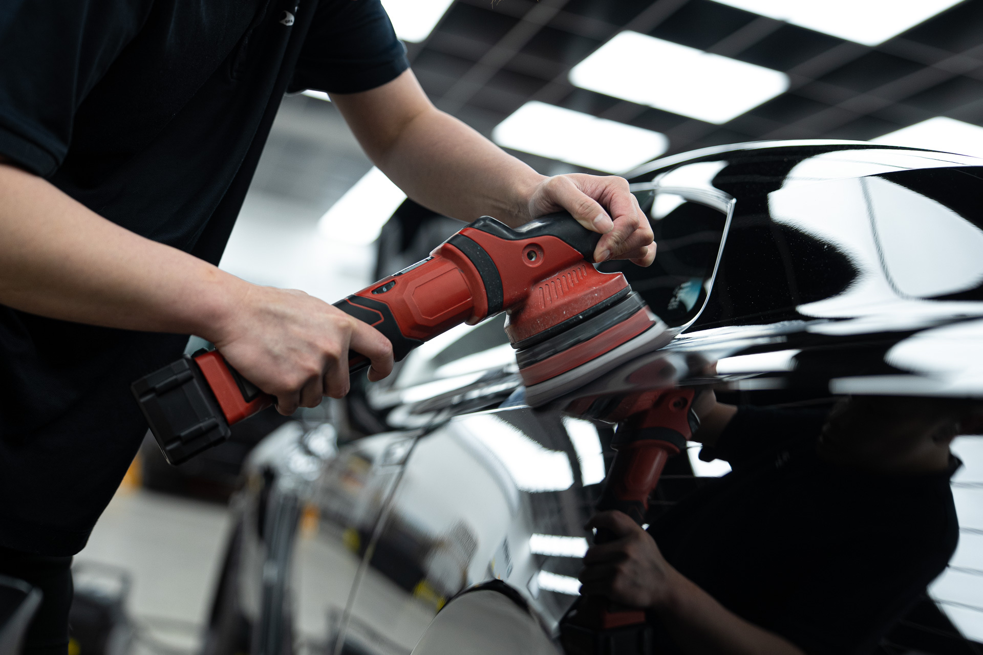 Machine polishing a black car before coating