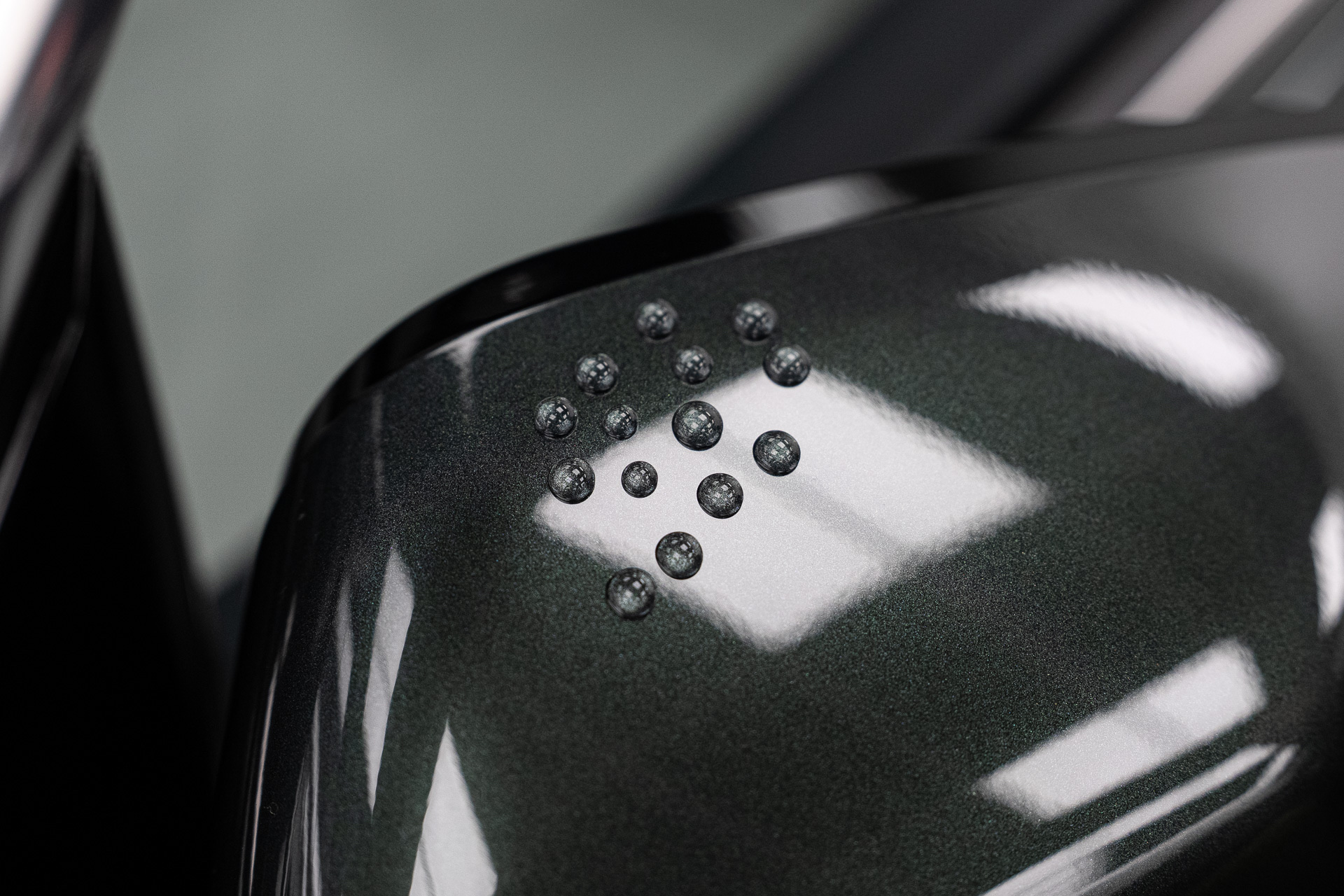 Water drops standing on a dark green coated panel