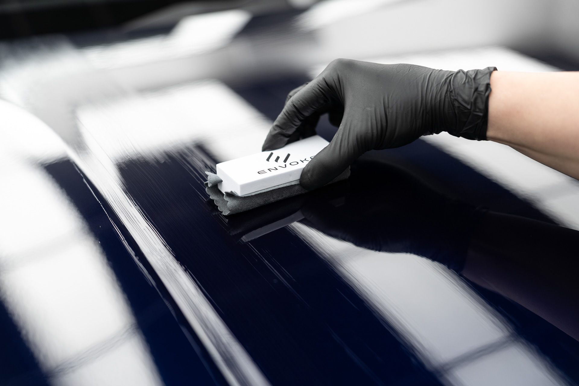Applying ceramic coating to a dark blue bonnet with an applicator block