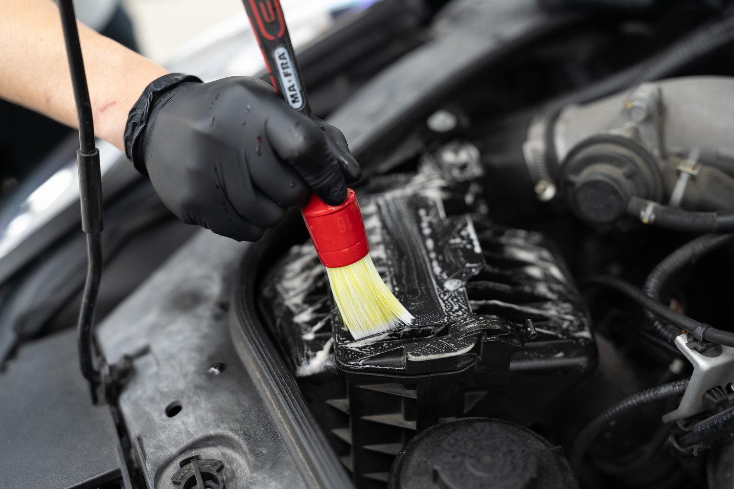 Detailing brush cleaning an engine bay