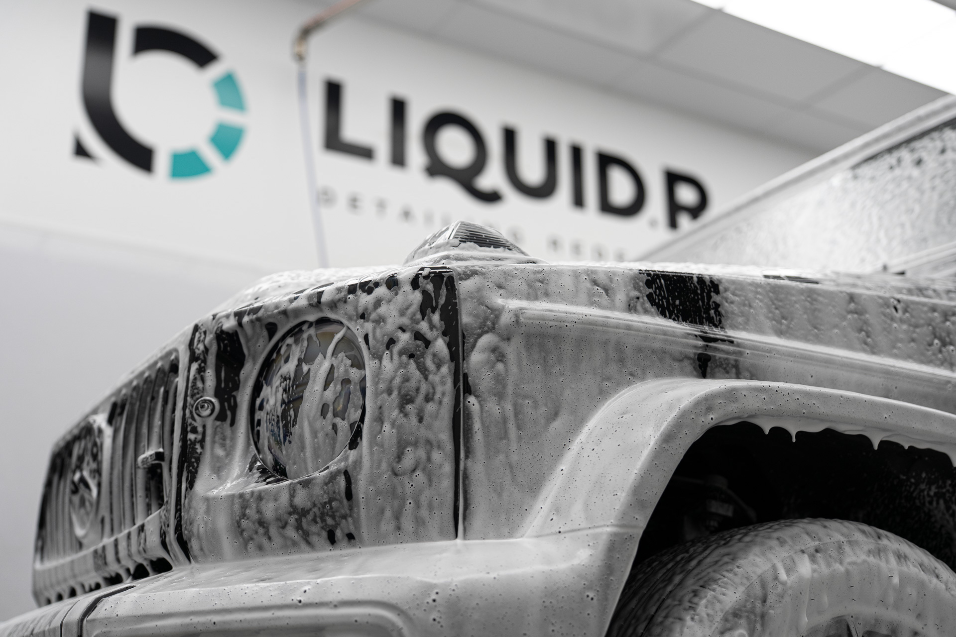 Snow foamed Mercedes G Wagon in front of the Liquid R sign