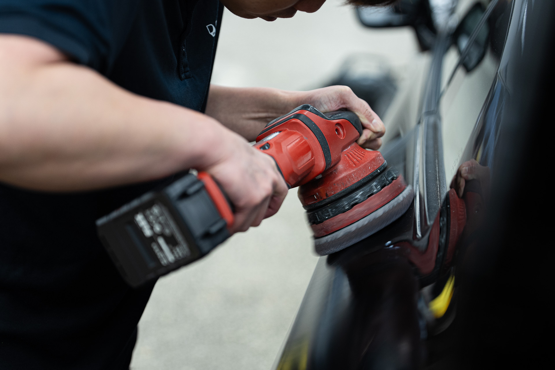 Machine polisher on a black panel during paint correction
