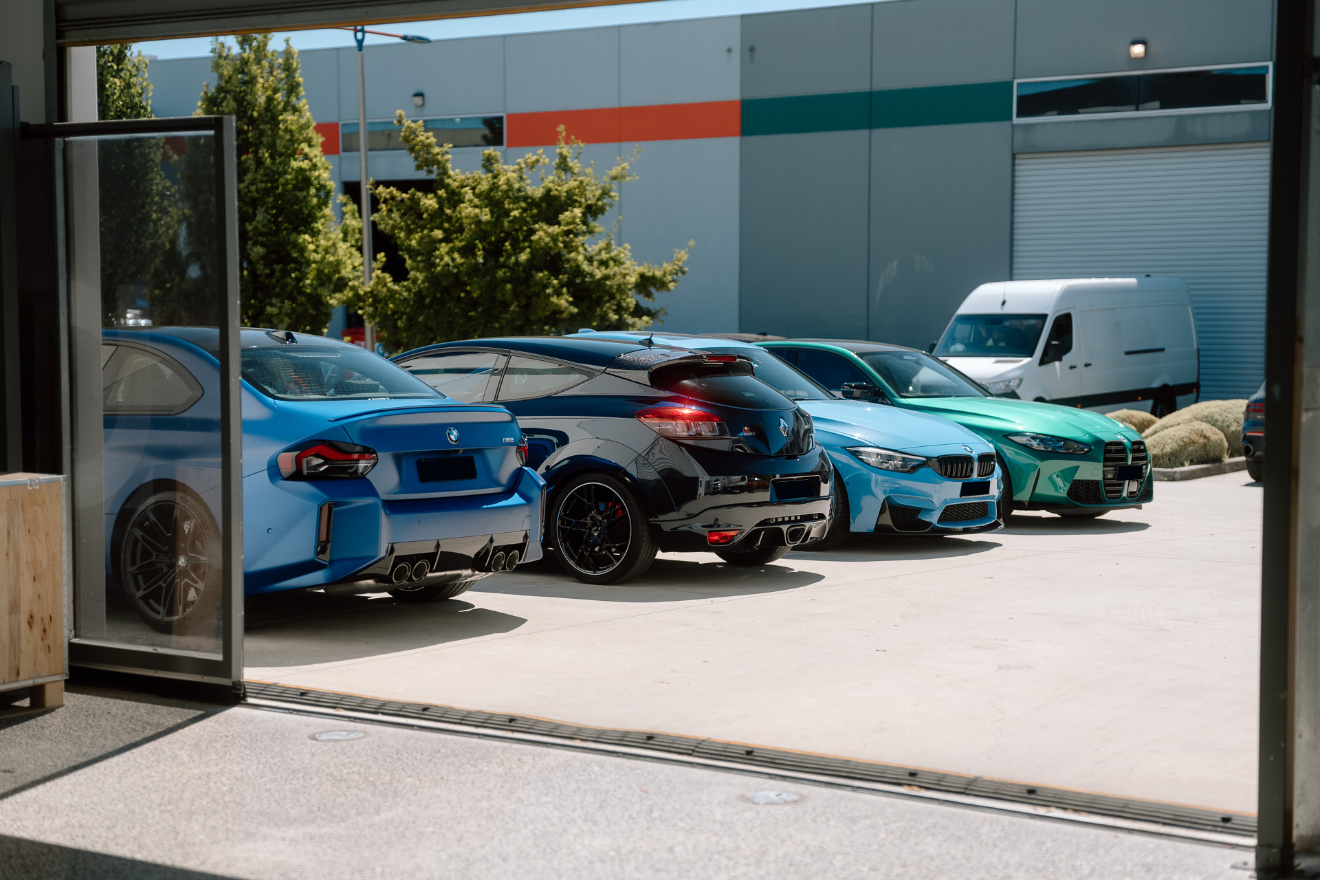 BMW M cars lined up at the Liquid R workshop entrance in Mitcham