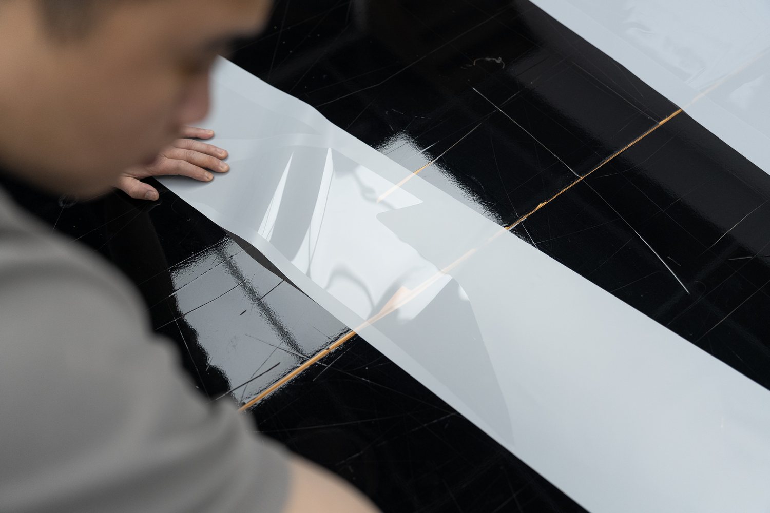 Paint protection film being trimmed on a panel