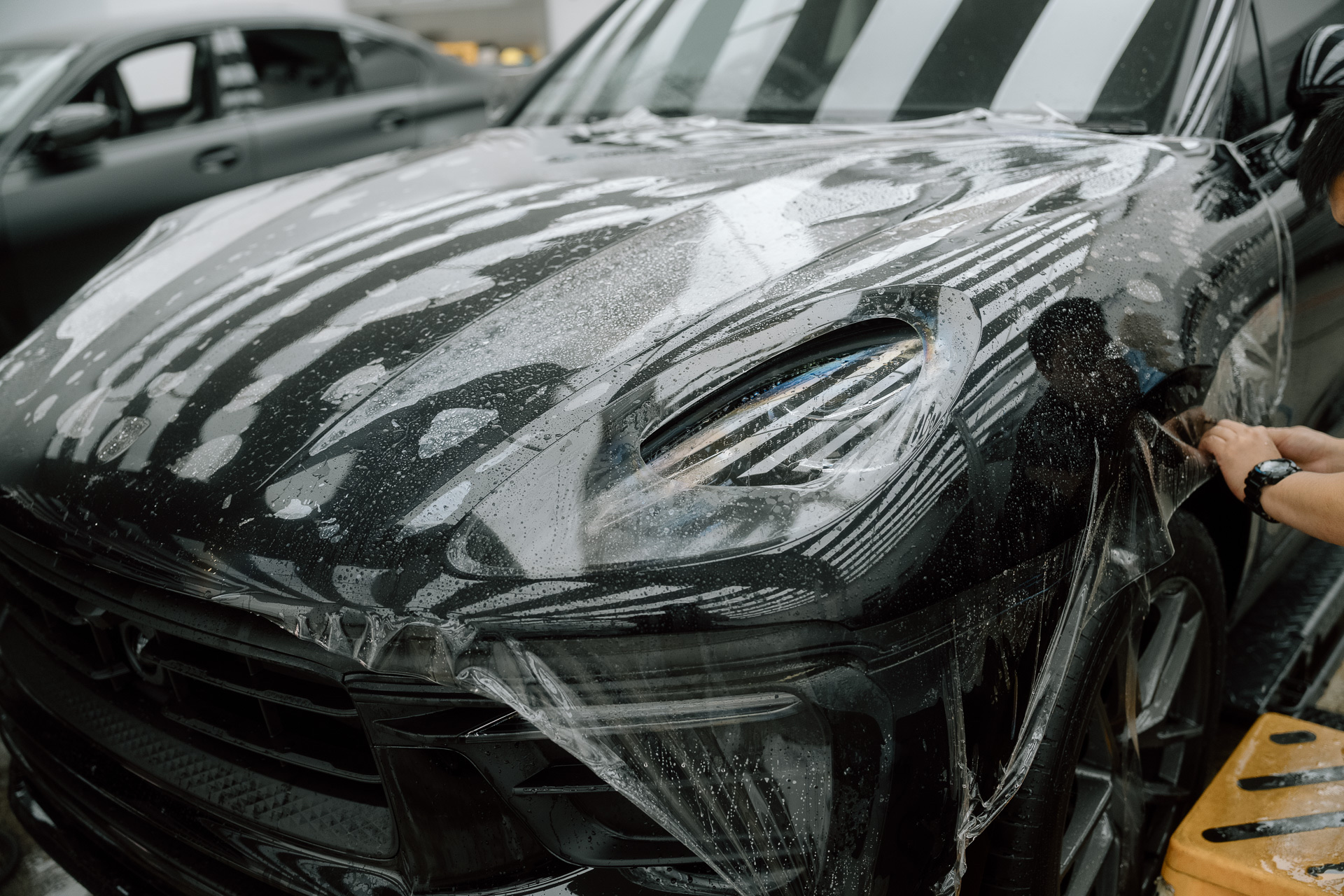 Wet paint protection film being squeegeed onto a bonnet