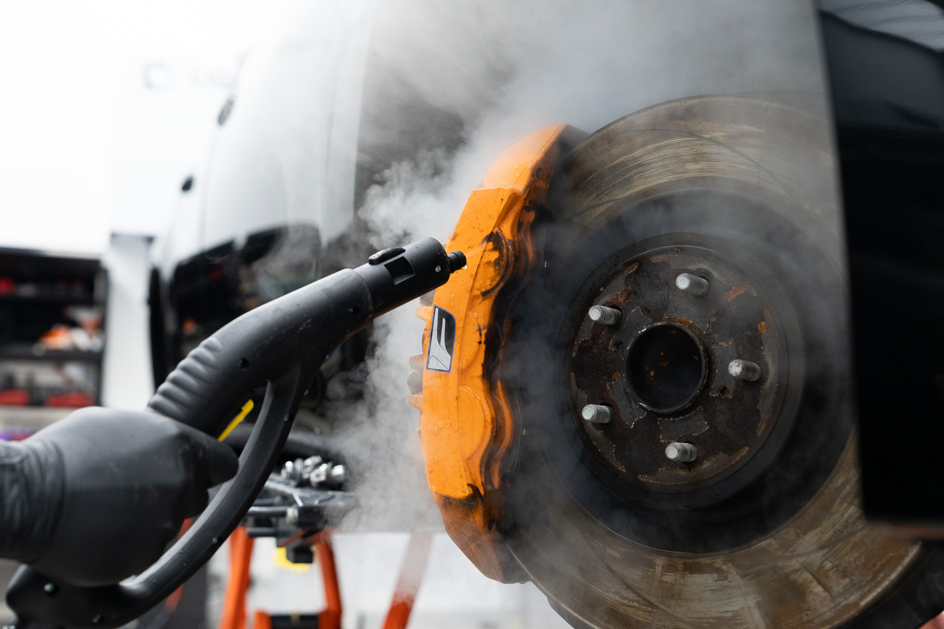 Steam cleaning a brake caliper during prestige detailing