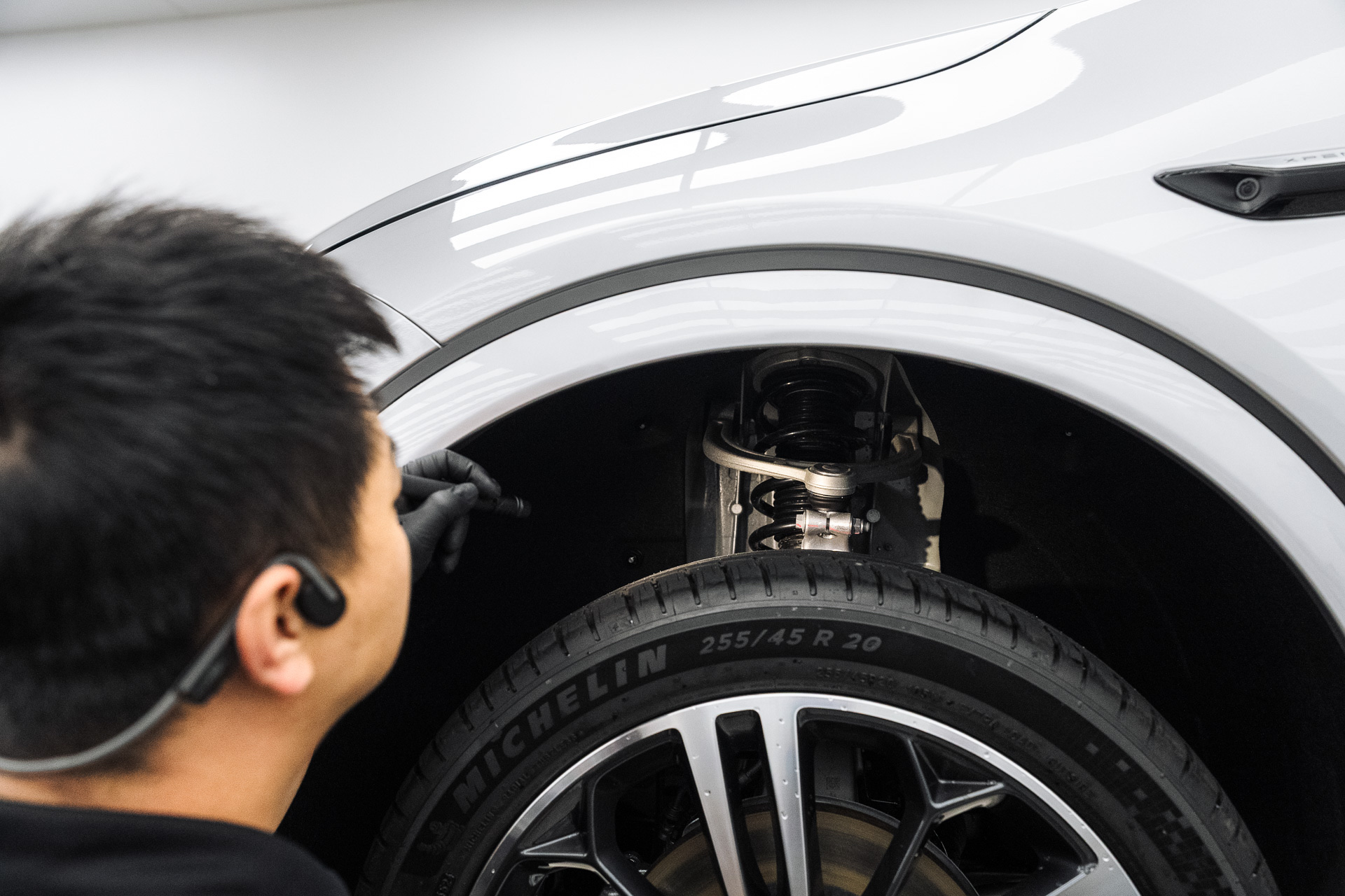 Mechanic inspecting the wheel and brake of a white BMW