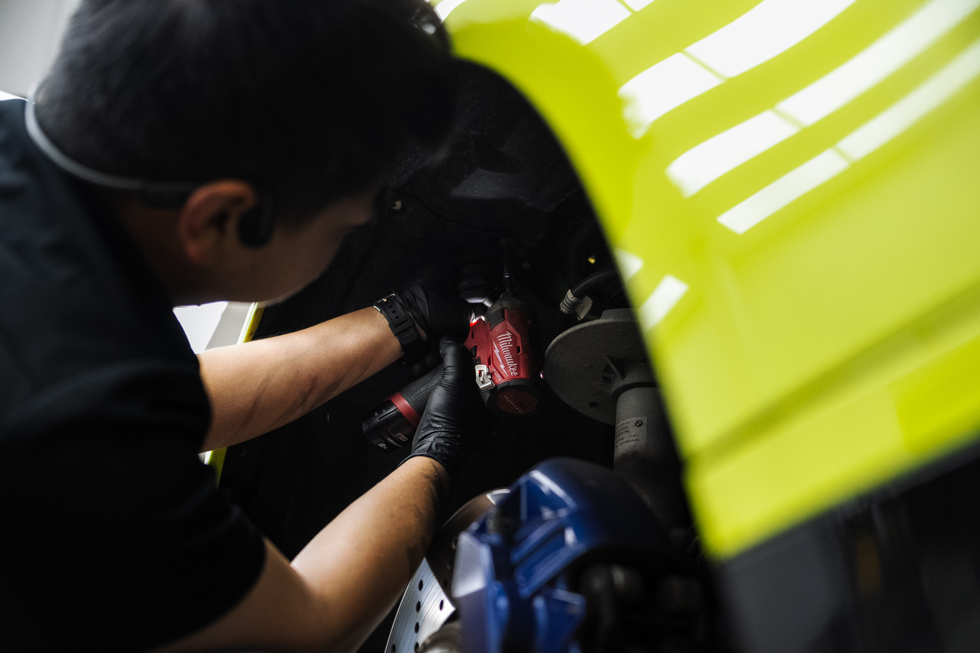 Mechanic working under the bonnet of a yellow BMW