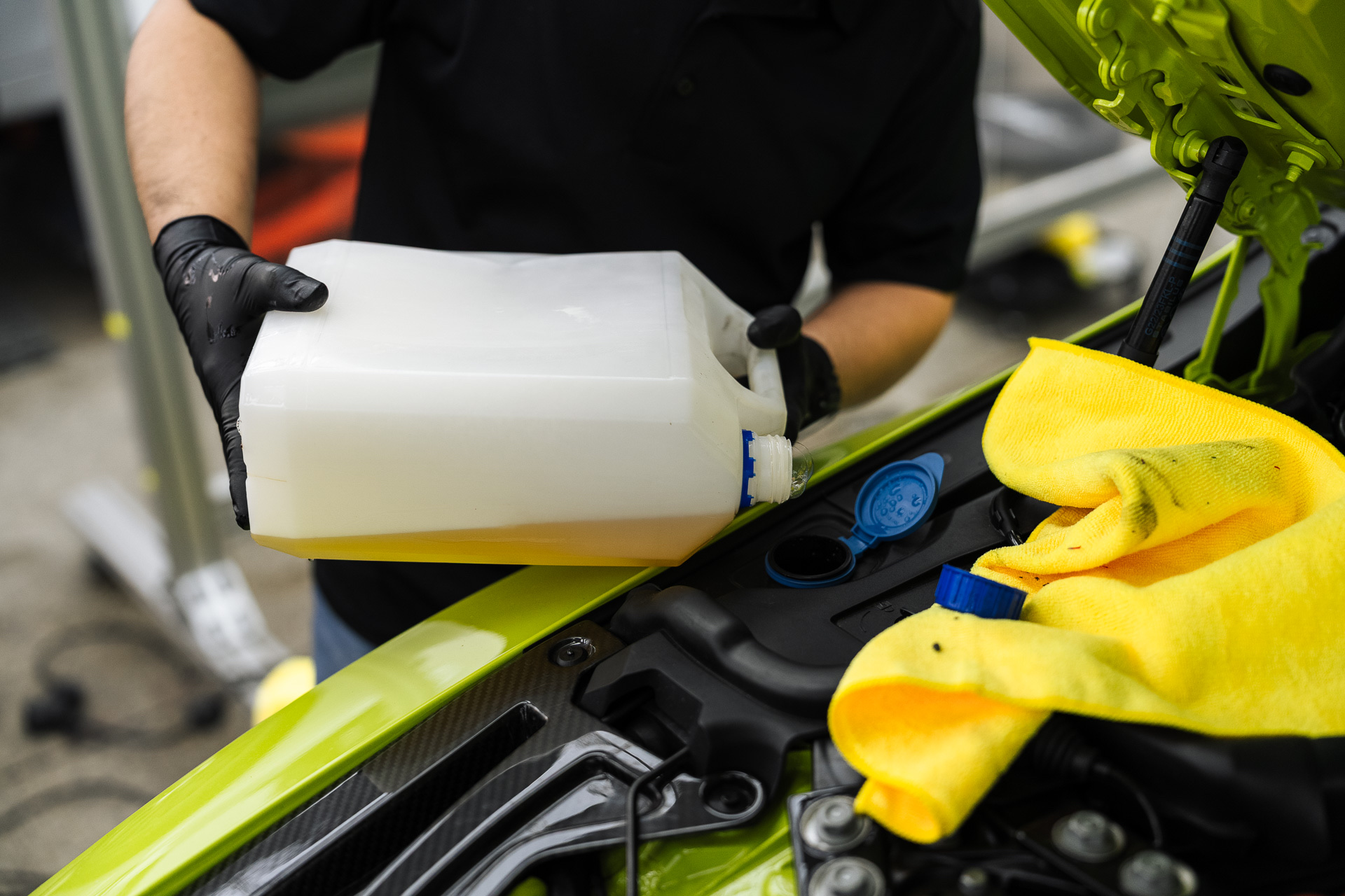 Mechanic topping up fluids on a yellow BMW