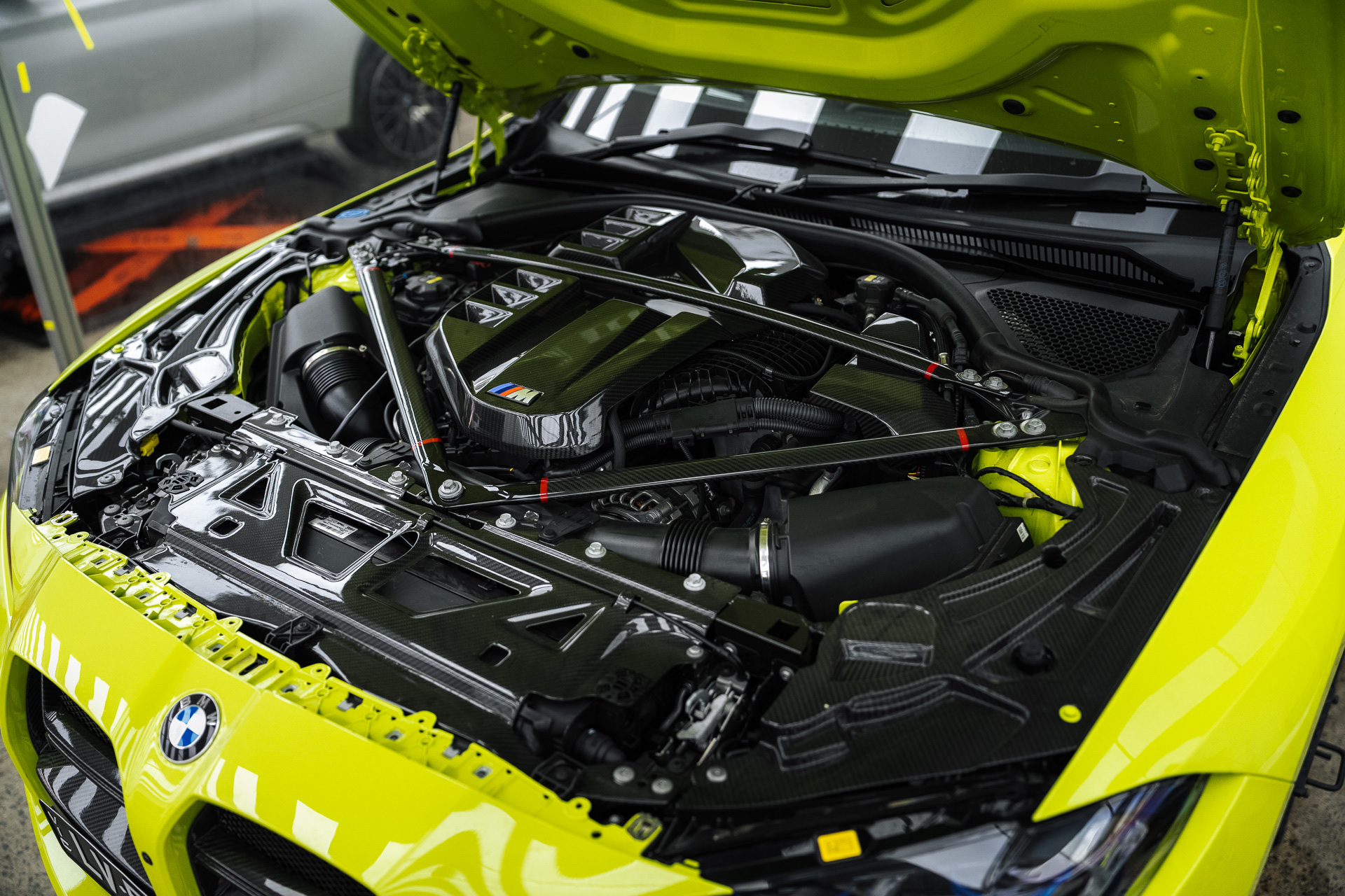 Engine bay of a yellow BMW M with strut brace
