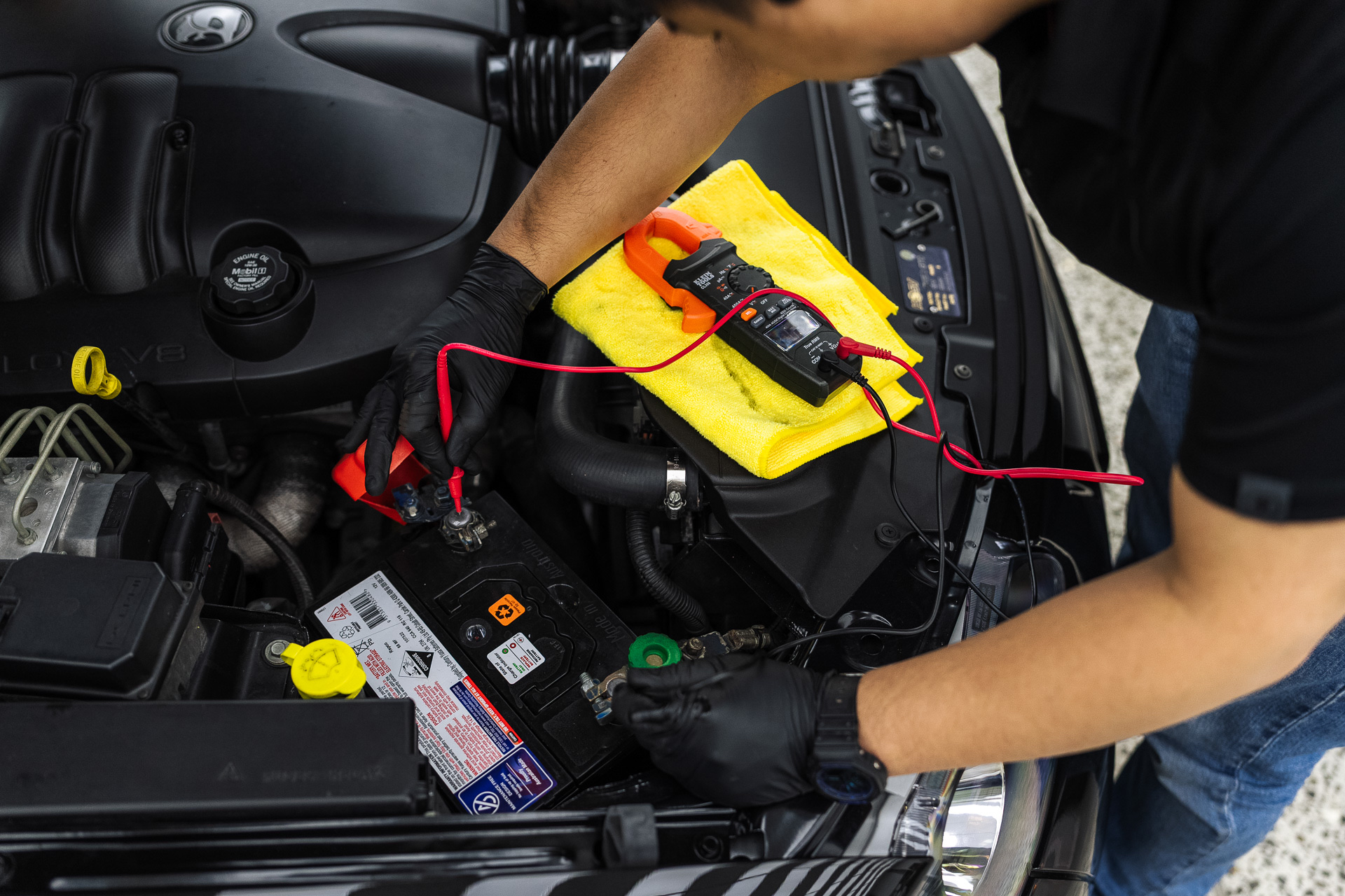 Mechanic testing a car battery with a multimeter