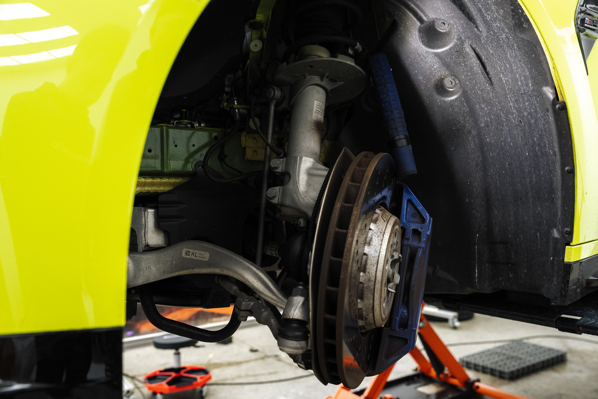Brake and suspension of a yellow BMW on a hoist