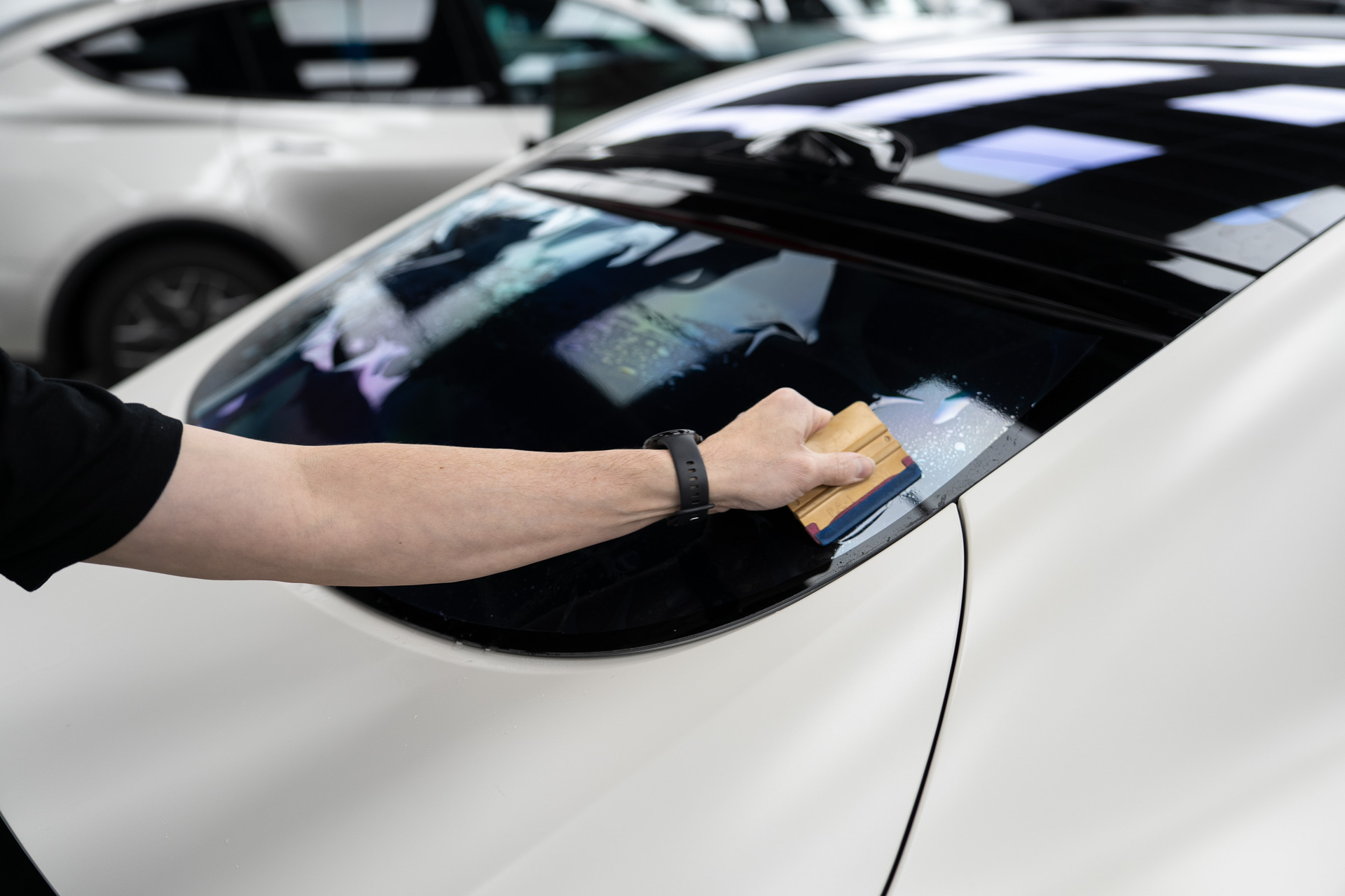 Squeegeeing window tint on a white car